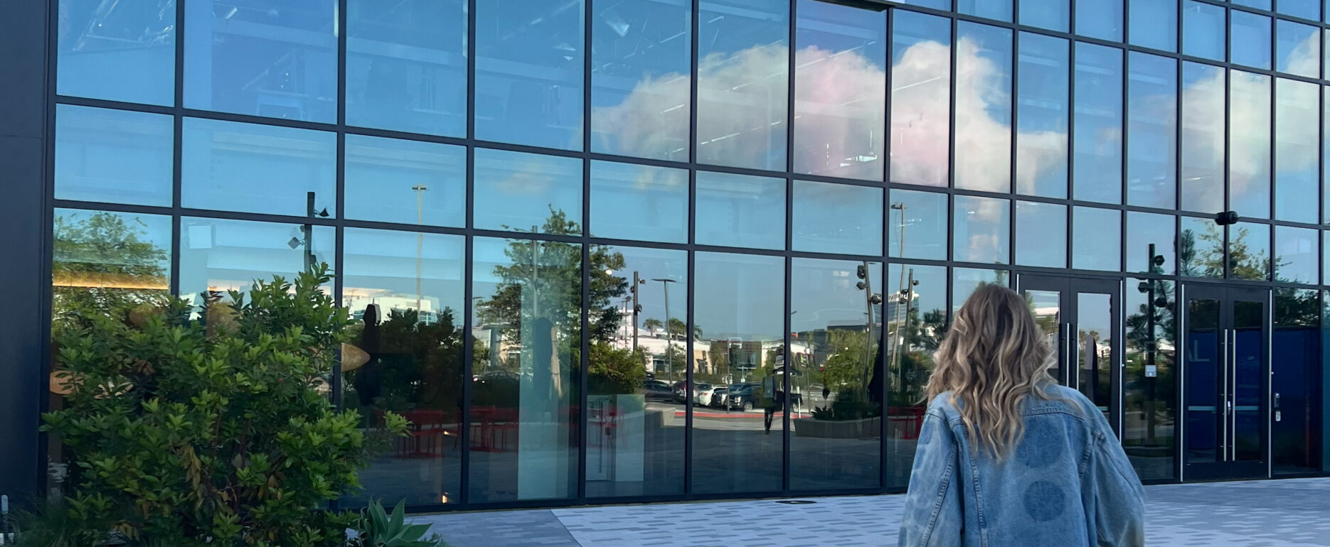 Jera Bean walking towards a glass building that reads "Loreal"