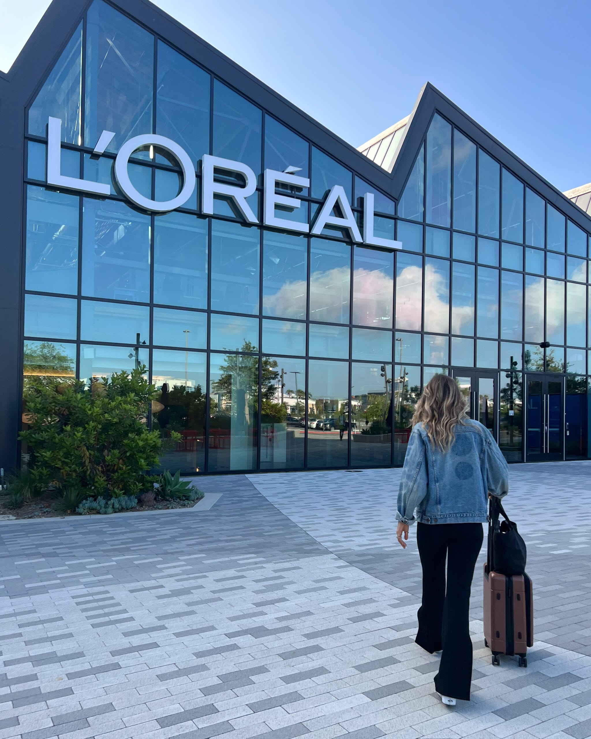 Jera Bean walking towards a glass building that reads "Loreal"