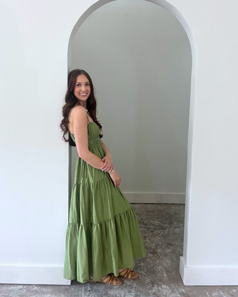 Woman in green dress posing in a white archway for a social media content shoot